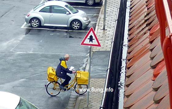 Postbote auf dem Fahrrad bei Regen