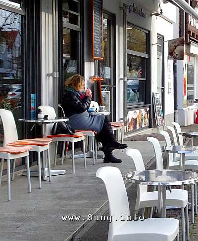 Raucherin in einem leeren Strassencafe - dick eingepackt