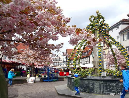 Rosa Blüten und gelg-grüner Osterbrunnen