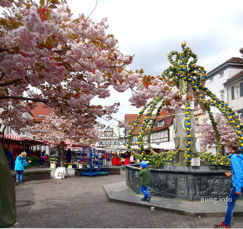 Rosa Blüten und gelg-grüner Osterbrunnen