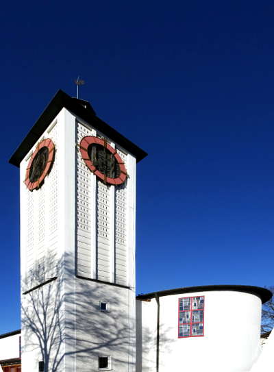 Weiße Kirche mit Baumschatten vor blauem Winter Himmel