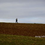 Spaziergänger vor grauem Himmel, dunkles Feld
