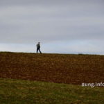 Spaziergänger vor grauem Himmel, dunkles Feld