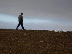 Spaziergänger vor grauem Himmel mit blauem Streifen