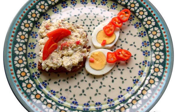 Paprika, Eier, Apfel auf einem bunten Keramikteller angerichtet