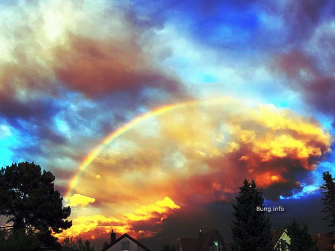 Feuriger Regenbogen vor blauem Himmel