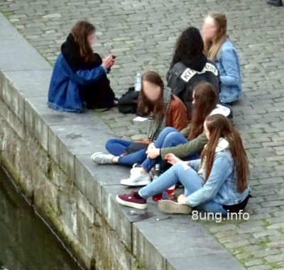 Mädchen sitzen auf den Pflastersteinen am Fluss