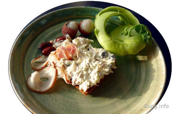 Litschis, Kohlrabi, Wacholderschinken, Kürbiskerne mit Frischkäse nach der Zubereitung auf einer Scheibe Vollkornbrot