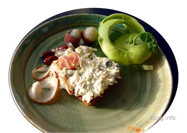 Litschis, Kohlrabi, Wacholderschinken, Kürbiskerne mit Frischkäse nach der Zubereitung auf einer Scheibe Vollkornbrot