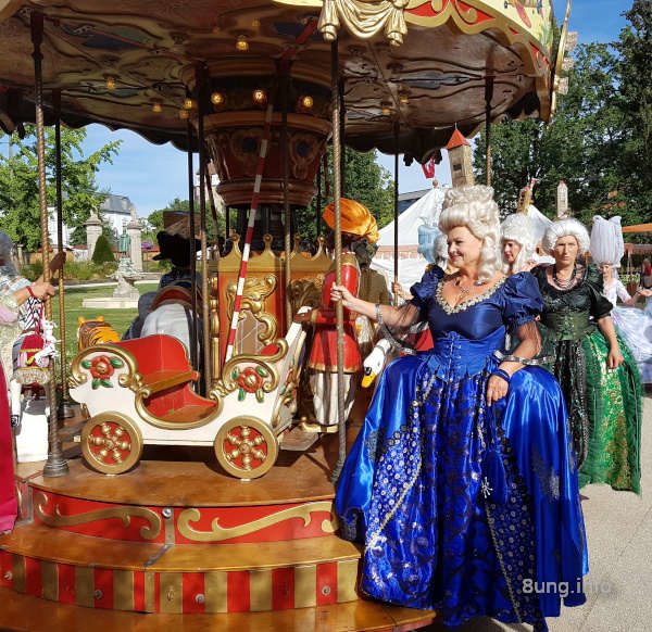 Dame im blauen Rokokokleid auf einem Karussell