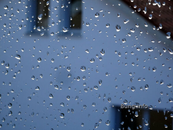 Wassertropfen auf der Scheibe nach einem Regen. Gegenüberliegende Hausfassade