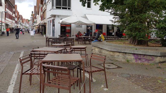leere Tische und Stühle im Strassencafe, graue Wolken
