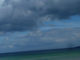 einsame Frau am Strand, viele Wolken, Wasser grün bis blau