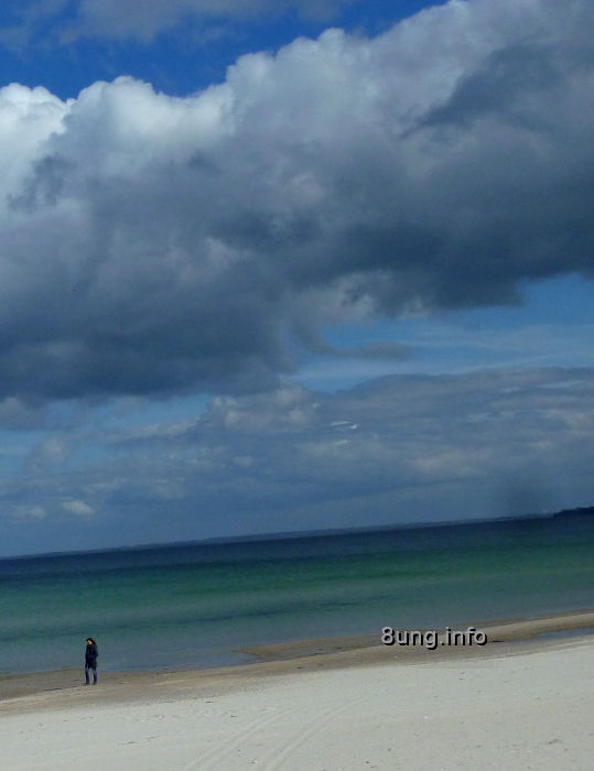 einsame Frau am Strand, viele Wolken, Wasser grün bis blau