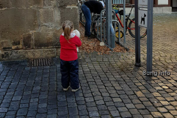 Wetter, Kind mit rotem Pullover, feuchte Pflastersteine, leichter Sonnenschein