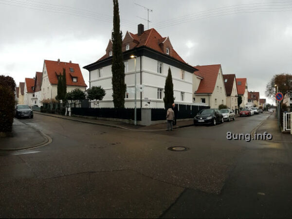 Straßenkreuzung mit grauen Wolken, weißes Haus, Passanten