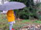 Kind mit Regenschirm und gelber Jacke
