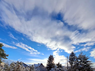Schnee auf Bäumen, blauer Himmel, zerfetzte Wolken