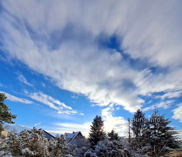 Schnee auf Bäumen, blauer Himmel, zerfetzte Wolken