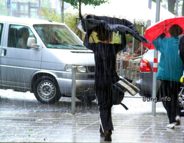 Wetter Eisheilige: strömender Regen, leute mit Schirm und Cape über dem Kopf als Regenschutz