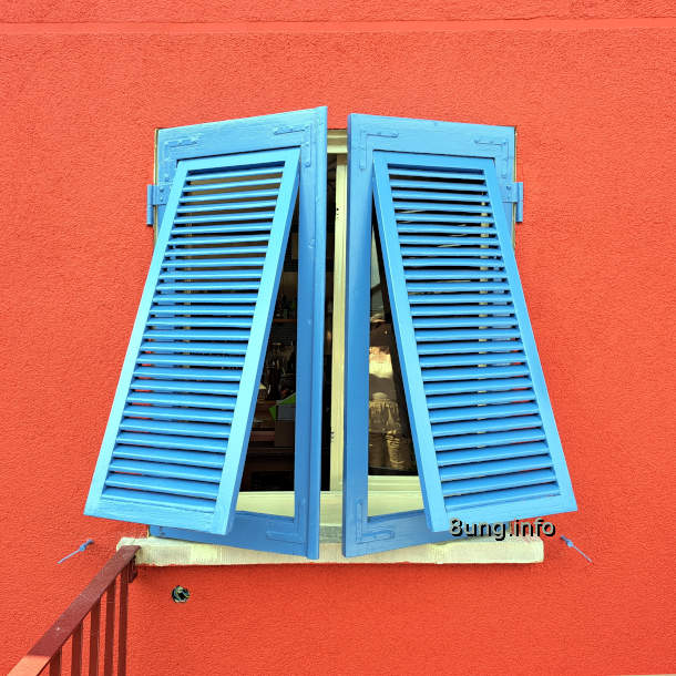Blaue Fensterläden vor einer roten Wand