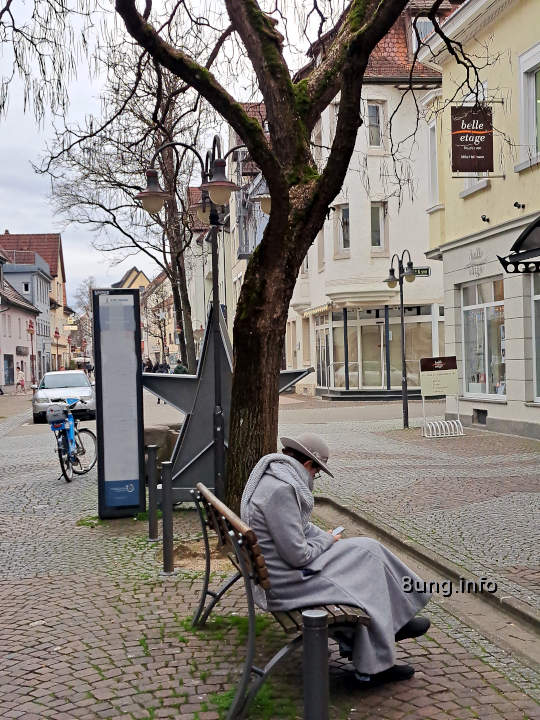 Dame in Grau auf einer grauen Bank unter grauem Himmel