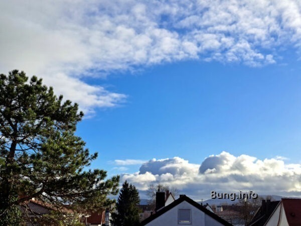 Blauer Himmel mit einem Wolkengebirge, darüber zerfetzte Wolken