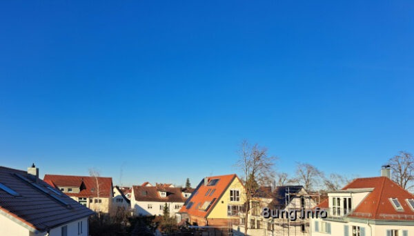 strahlend blauer Himmel über einer Häuserreihe