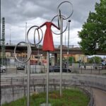 „Die Reisende“ – Kunst am Bahnhof Wendlingen Am Bahnhof Wendlingen dreht sich eine Frau. Keine echte, sondern eine aus Metall – und ohne Kopf. Sie steht nicht einfach da, sie bewegt sich. Ganz langsam, einmal pro Minute, macht sie eine vollständige Drehung. Dabei gleiten große Ringe um sie herum – mal näher am Körper, mal etwas entfernt, als wollten sie sie einrahmen oder durchqueren.