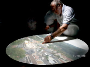 Ein Mann beugt sich über eine leuchtende Scheibe: Die Camera Obscura wirft das Bild einer Stadt wie von Zauberhand auf die Fläche