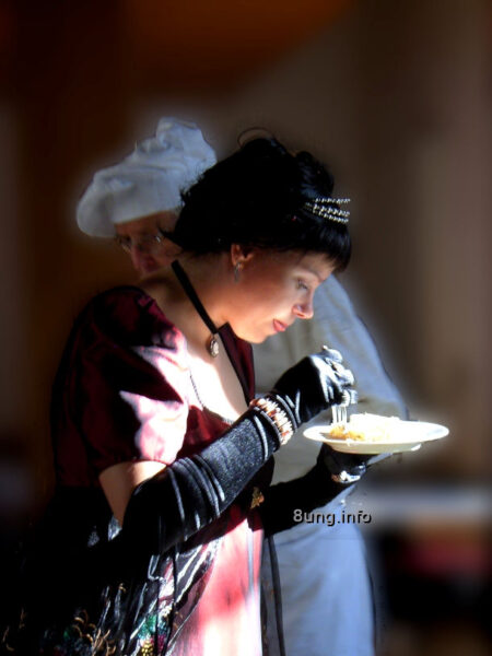 elegante Dame isst im stehen von einem Teller