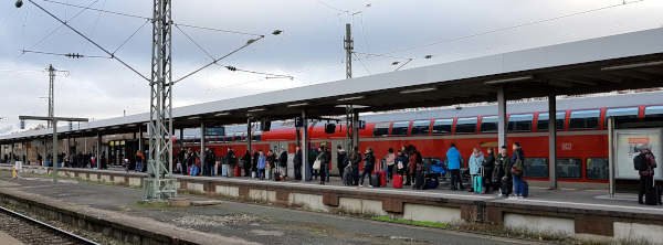 Reisende warten auf dem Gleis am Bahnhof