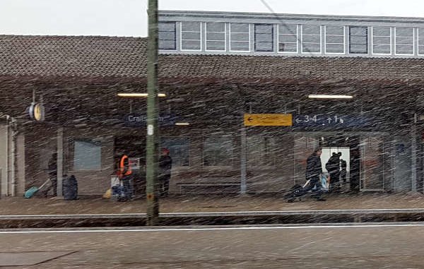 Schneegestöber auf dem Bahnhof, Reisende mit Koffern