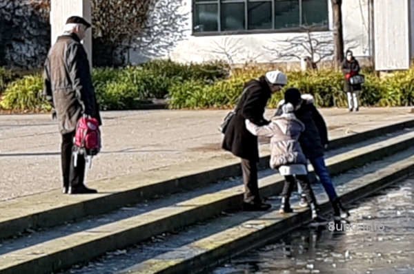 Kinder probieren, ob das Eis auf dem Wasser sie trägt